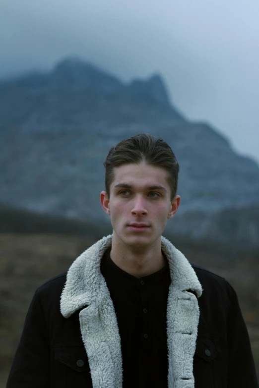 man with black and white coat outside under cloudy skies