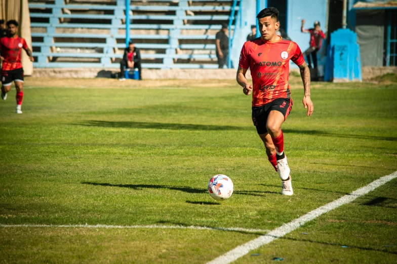 soccer player in uniform running to kick ball on green field