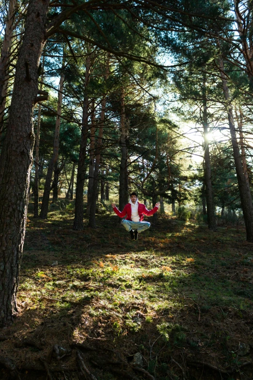 woman in red suit doing aerial trick in the woods