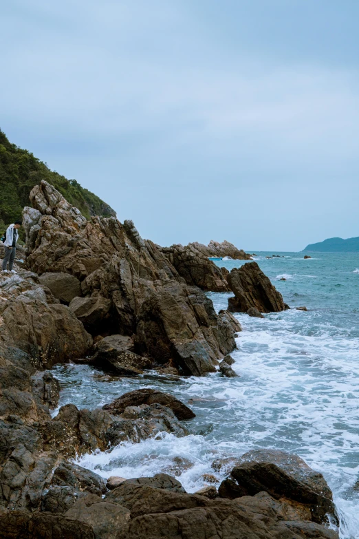 a person stands on the rocks at the beach