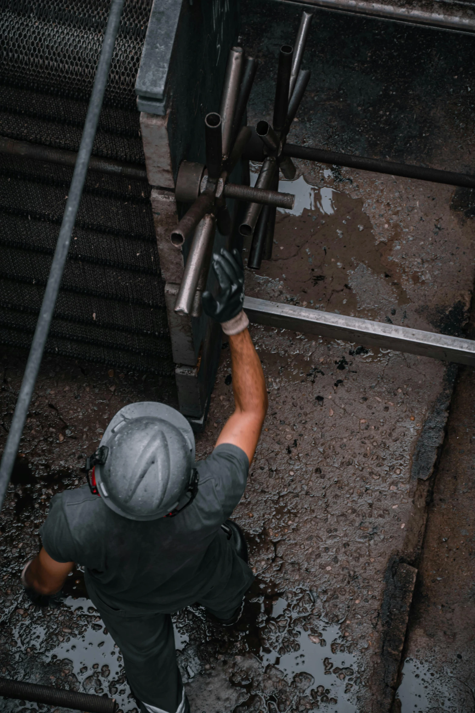 man with hat on working near metal pipes