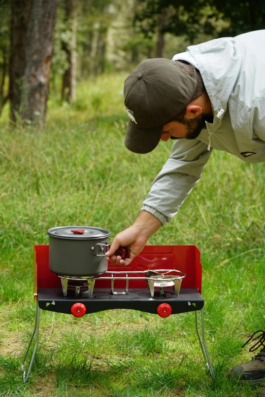 a man cooking on an outdoor stove with the lid off