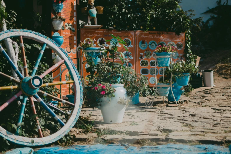 a wheel sits in a garden surrounded by flower pots and plant life