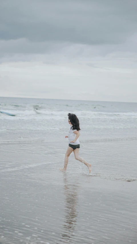 a little girl running across the beach with an umbrella