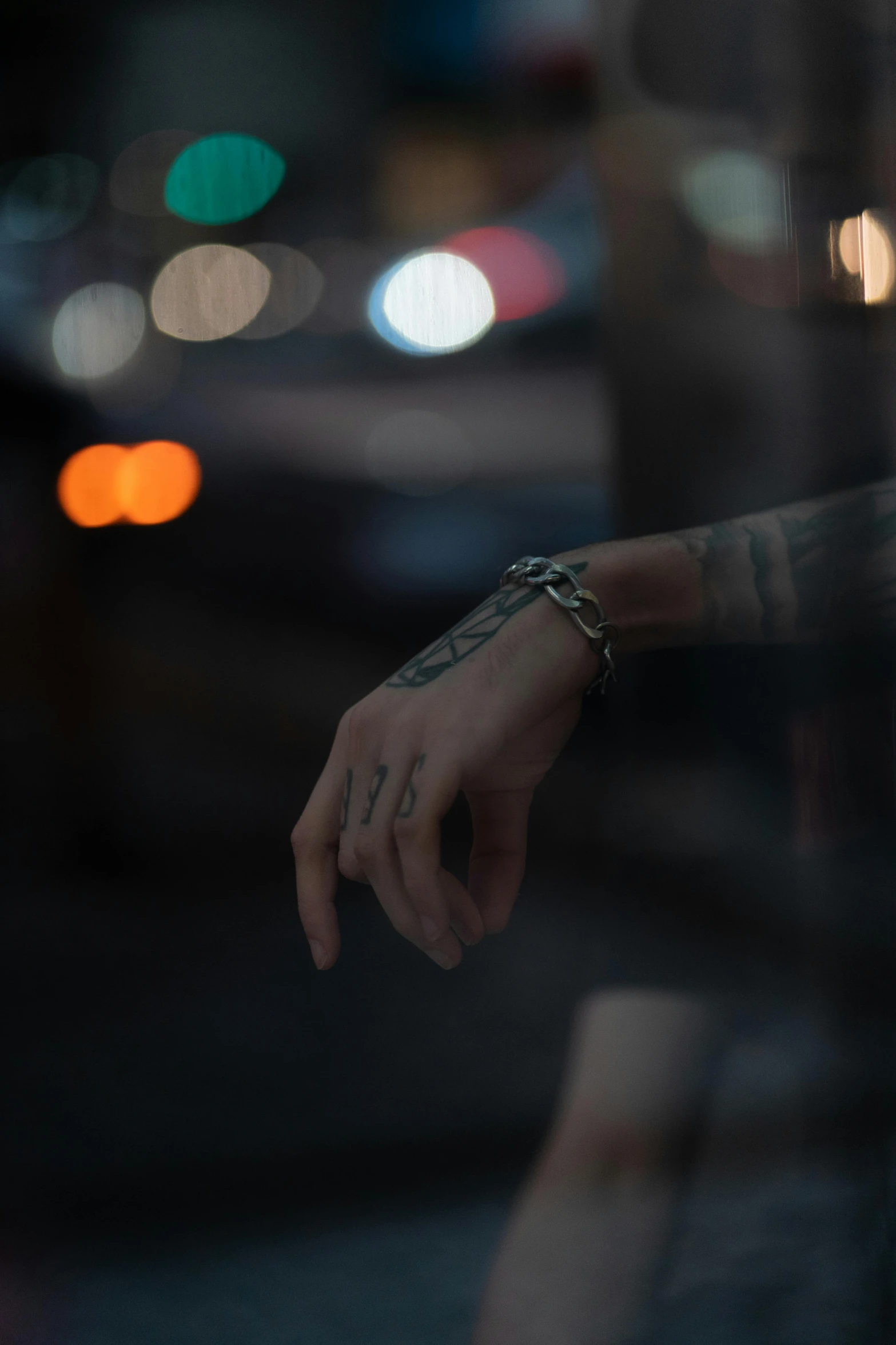 a person with a chain tattooed arm holding a cigarette