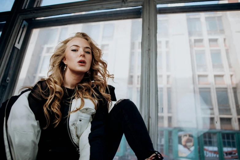 woman sitting on window sill in room with large windows