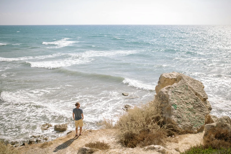 the boy is standing near the water looking at the waves