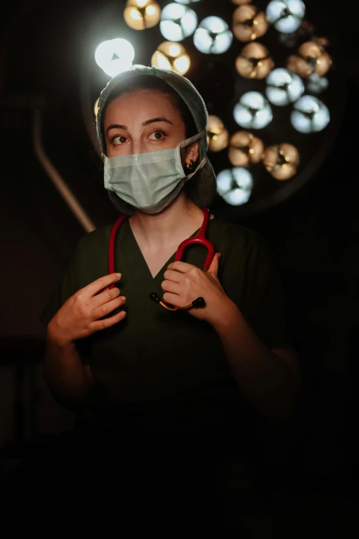 a woman with a surgical mask on holding a nurse's stethoscope