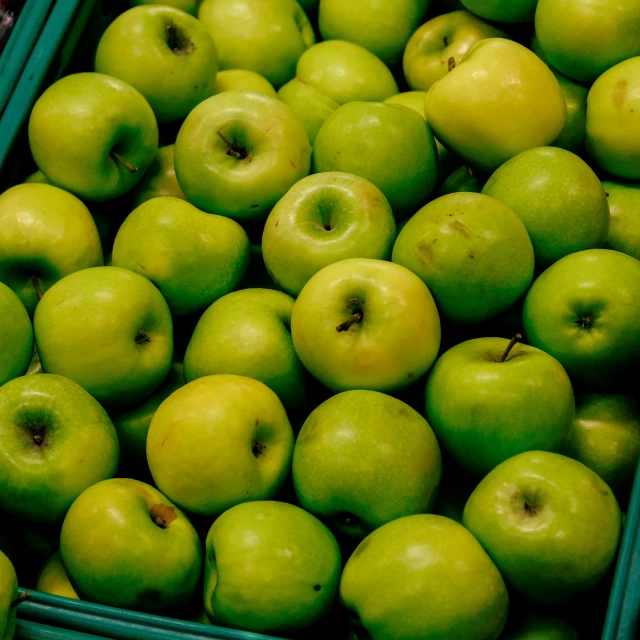 a bunch of green apples are sitting in a bin