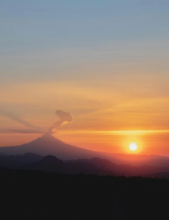 sunset over mountains with clouds and sun peaking out