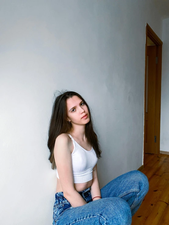 a girl is sitting on the floor with her pants exposed