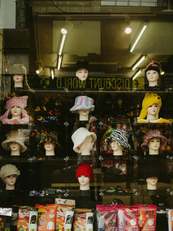 a group of mannequin heads sit in a store window