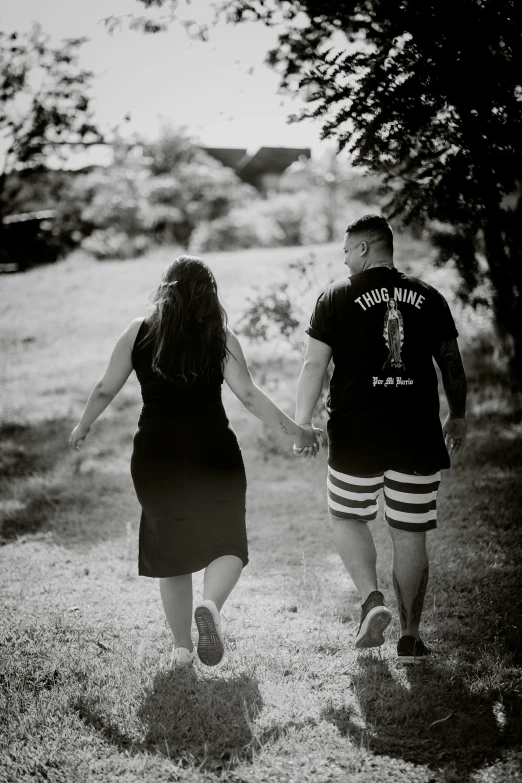 the couple is walking in the field holding hands