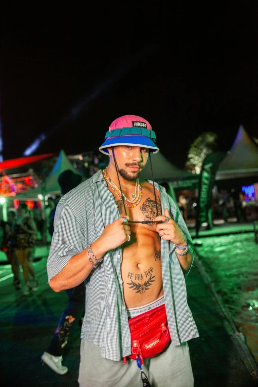 young man wearing a hat and jacket standing outside with a camera