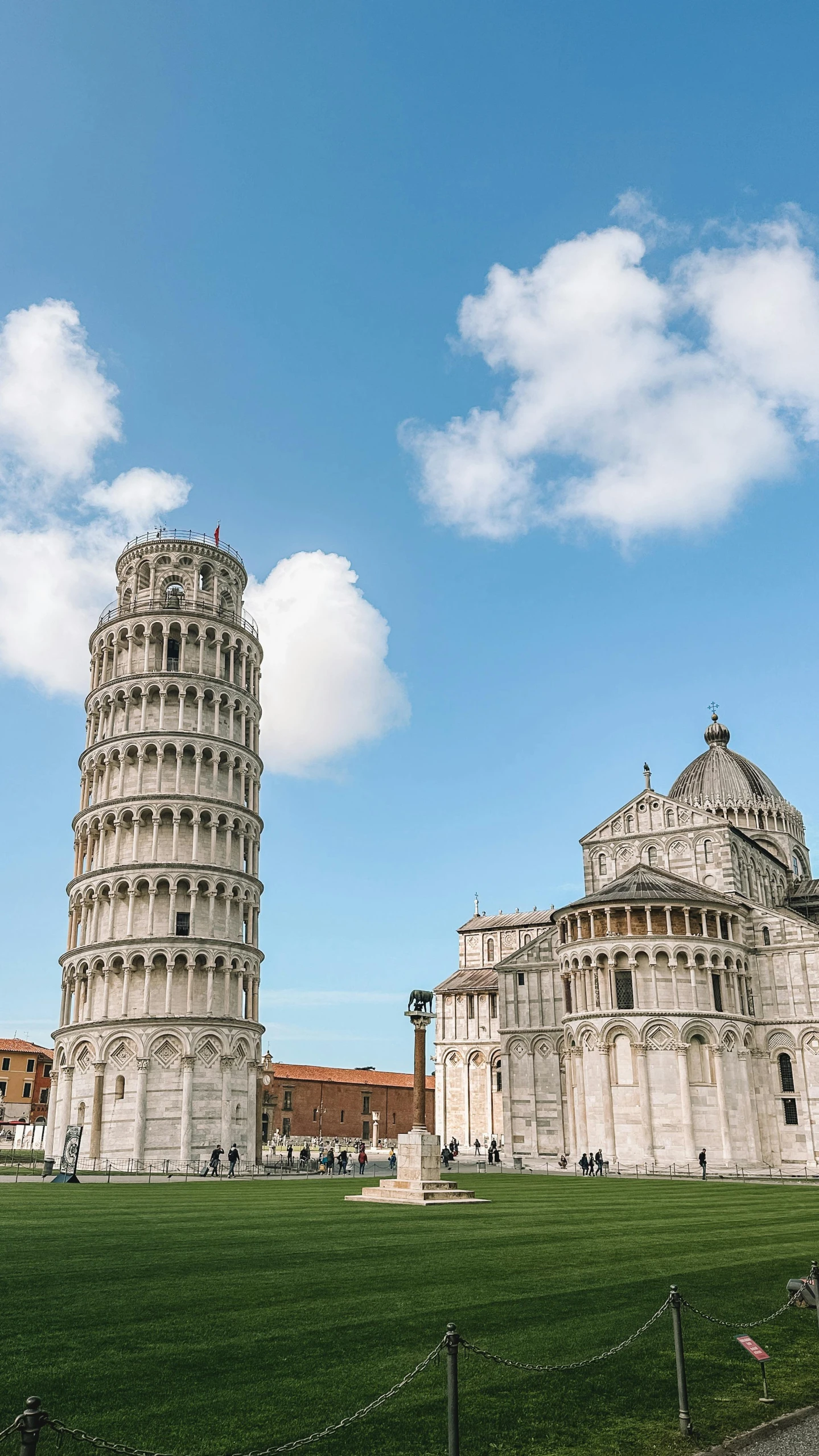 the leaning tower of pisa is behind a grassy field