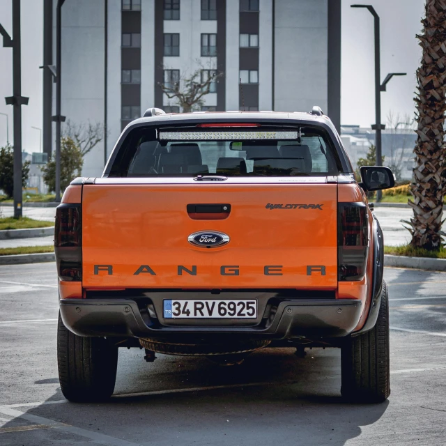 an orange pick up truck parked on the side of the road