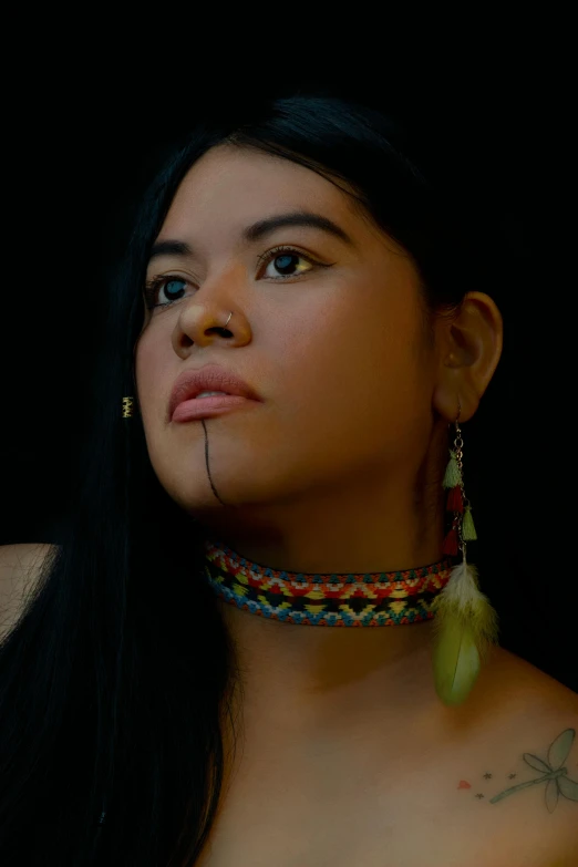 a close up view of a woman with two feathers on her neck