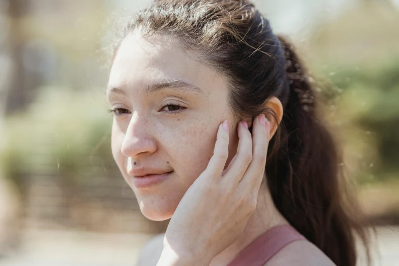 a young lady looking to the left and holding a cell phone to her ear