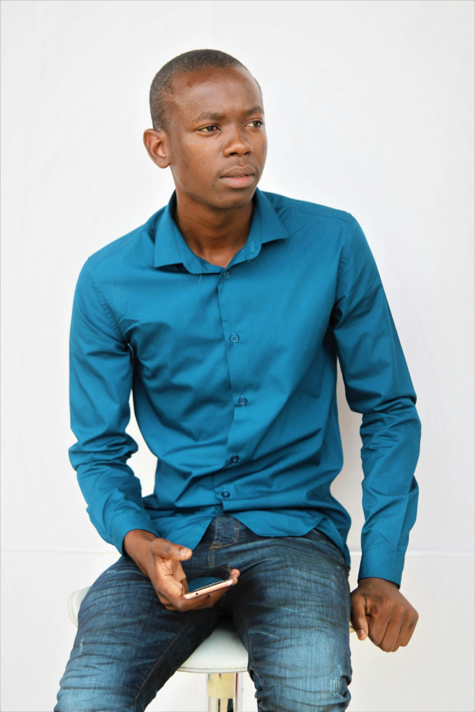 young man in blue shirt sitting on a white chair