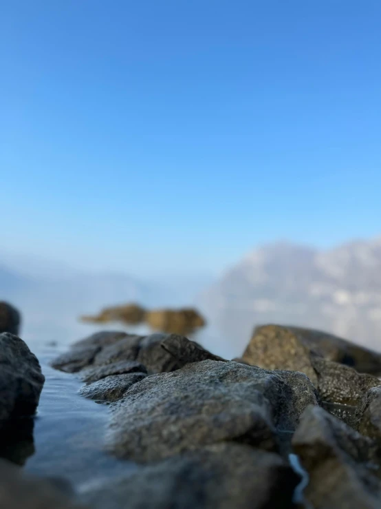 water with rocks in the foreground and mountains in the background