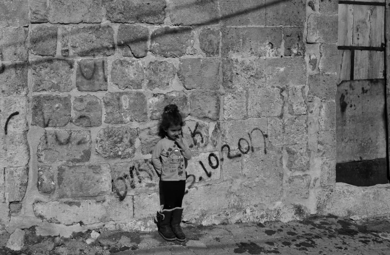 a girl with graffiti written on her face standing next to a brick wall