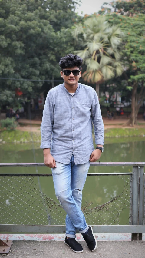 an indian man stands on a bridge near water