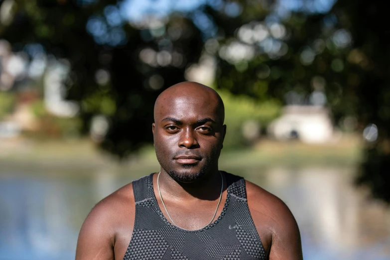 a man in a tank top stands by a body of water