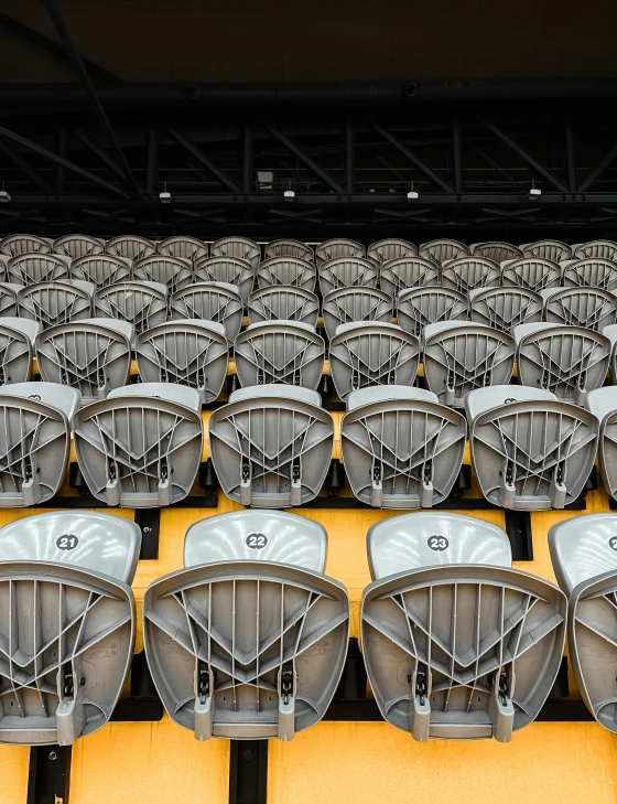 rows of chairs with black bases and yellow seats in a stadium