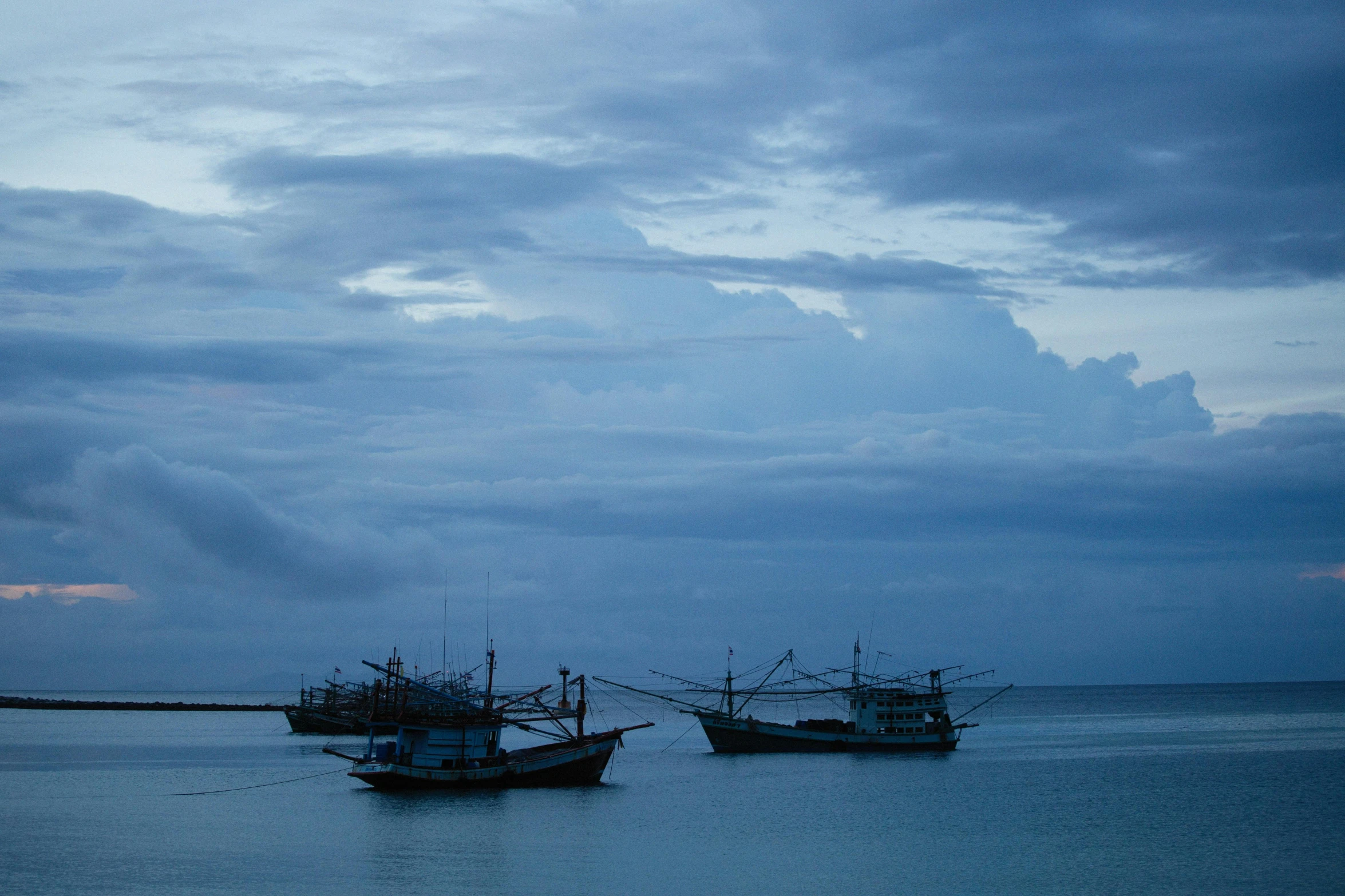 two boats in the middle of water at dusk