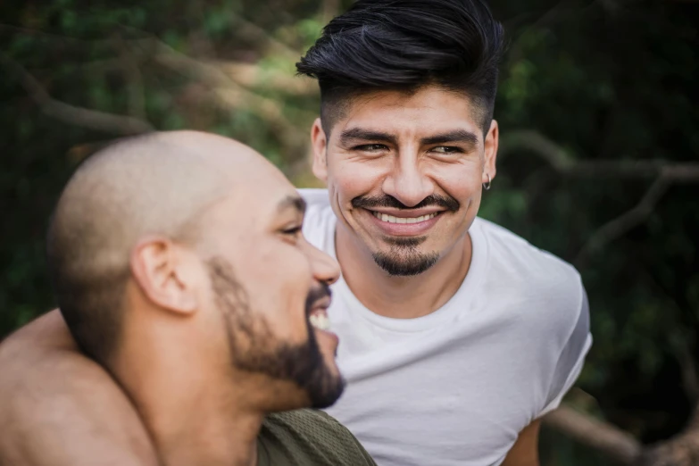 there is a smiling man and a bald male looking into each other's eyes