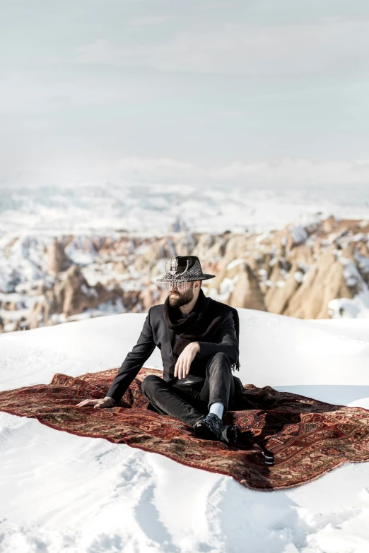 man sitting on top of snow covered mountain with scarf