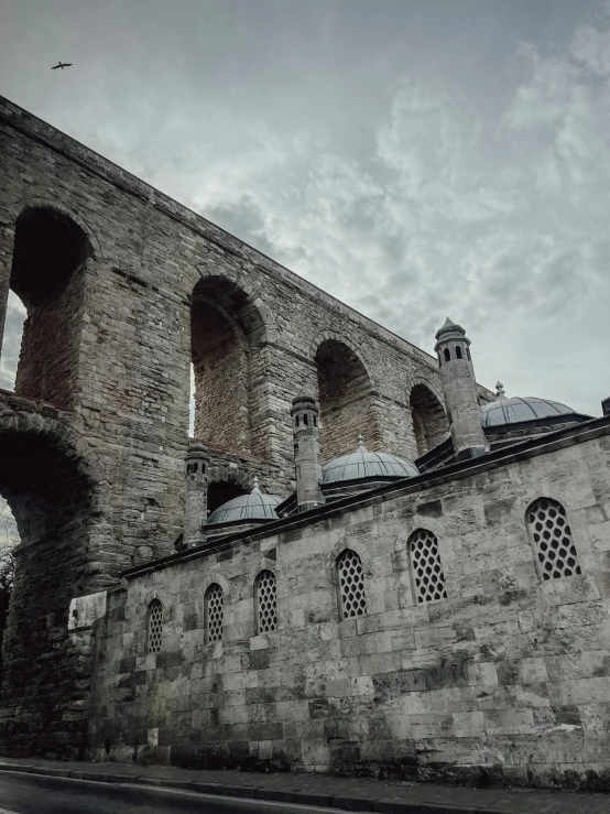 stone building with arched windows and walls under a cloudy sky