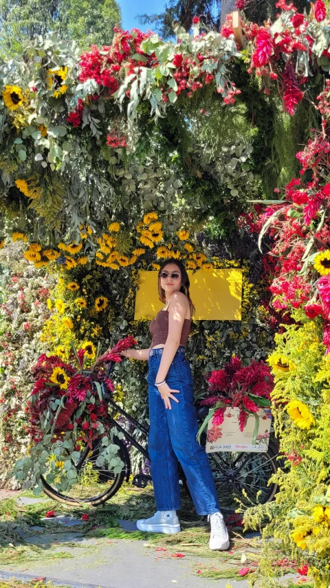 a girl stands near a bike under the flowers