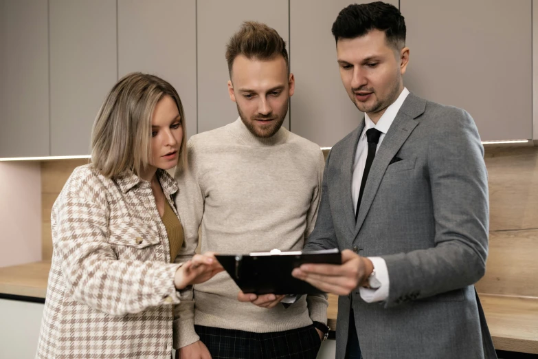 three men and a woman looking at an item on a digital tablet