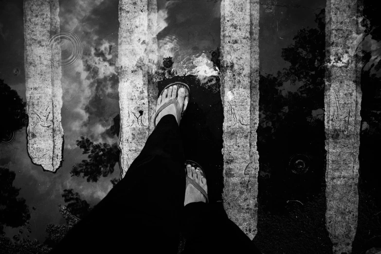 a black and white po of a person's feet in a forest