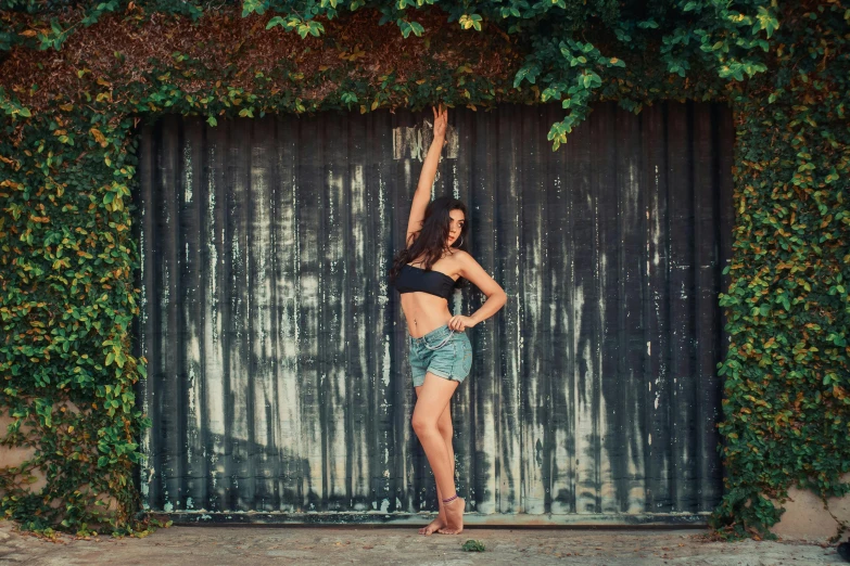 a girl stands in front of a fence wearing shorts