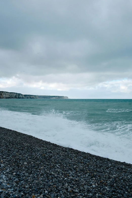 the sky has clouds and waves hitting the beach