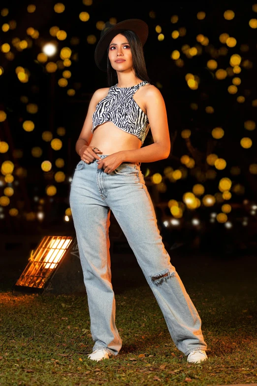 a woman wearing wide jeans stands in the grass