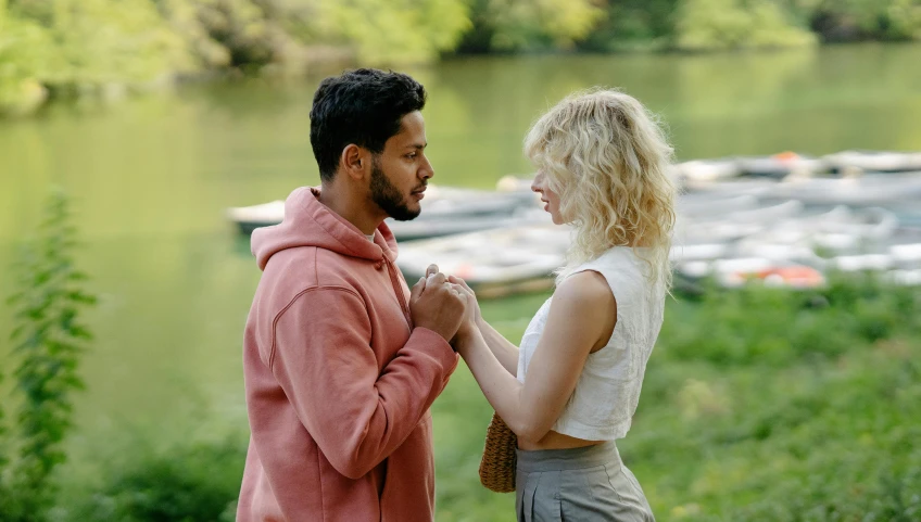 two people are standing near the water and a river