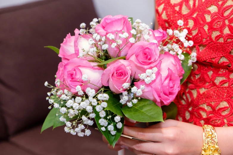 a woman holding a bouquet of pink roses