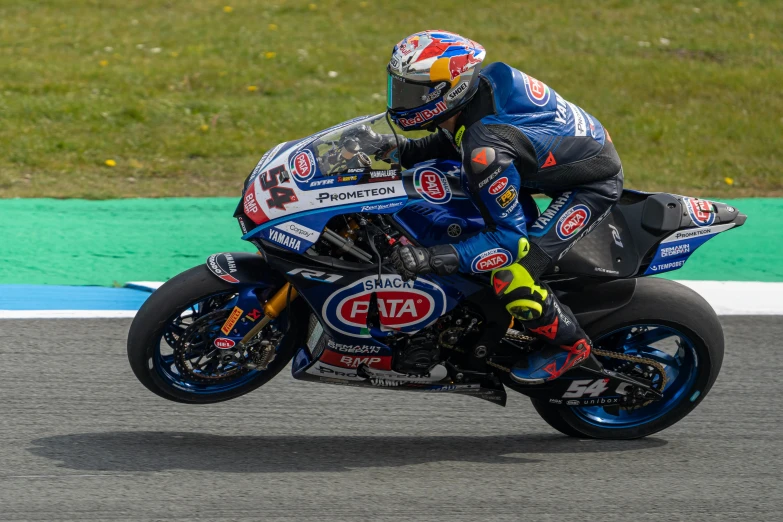 a man riding on the back of a motorcycle next to a grass covered field