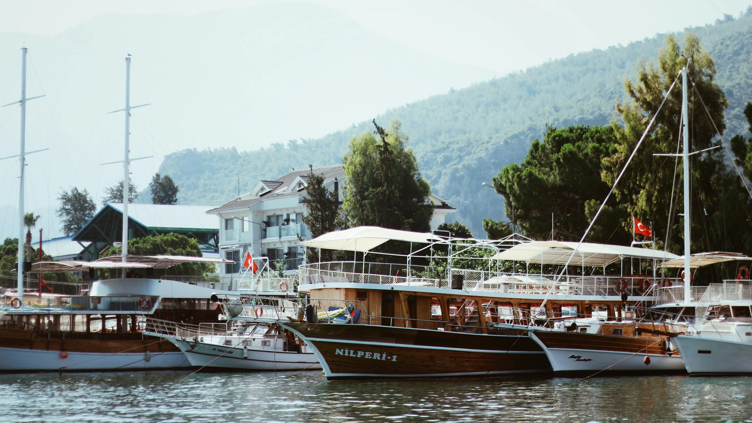 many boats in the water near a hill