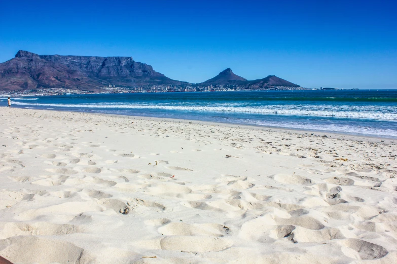 a sandy beach that has some mountains in the background