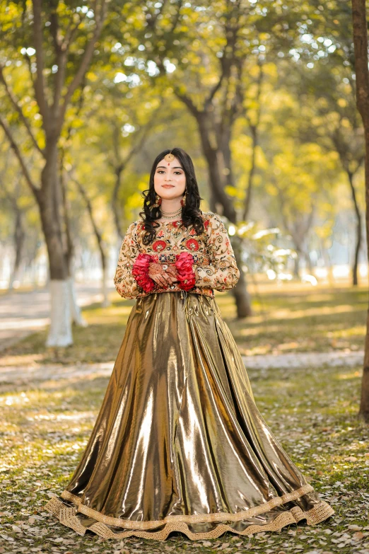 a woman in a long skirt and flowers standing in front of some trees