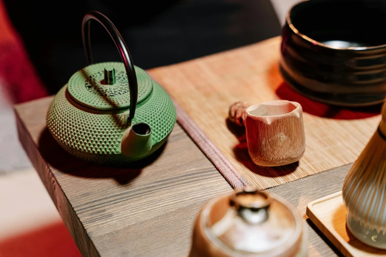 the top of a wooden table with a green teapot and a brown vase