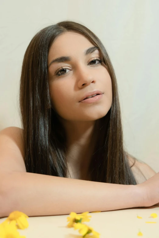 woman with long dark hair standing by white wall