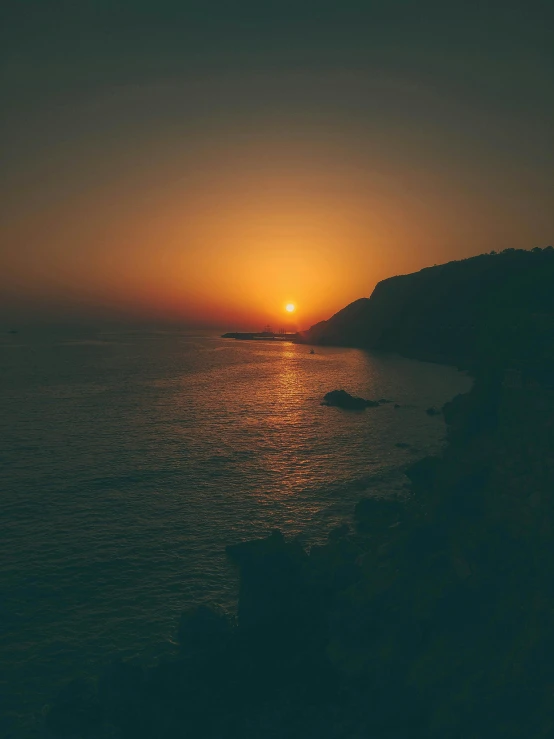 a boat sitting on top of the ocean at sunset