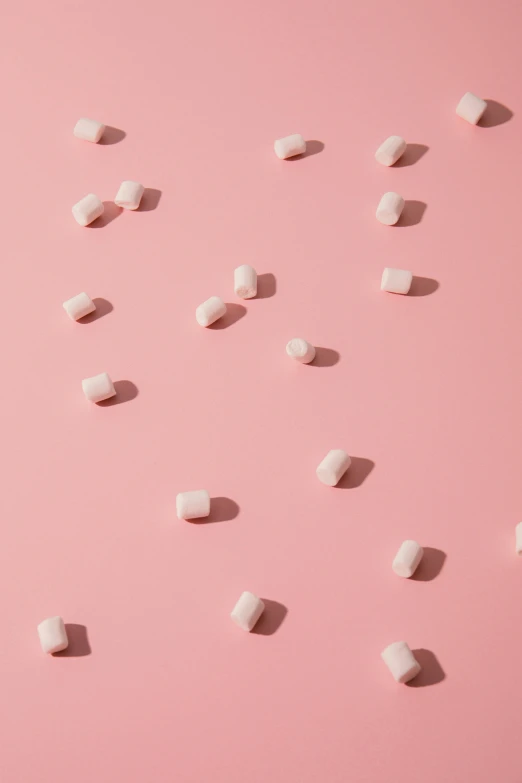 small white square objects scattered across a pink surface