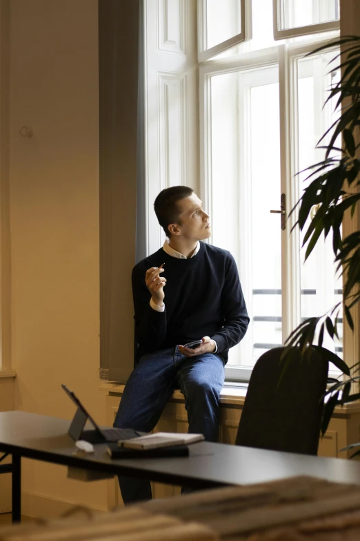 the man is sitting by his desk and holding a cellphone