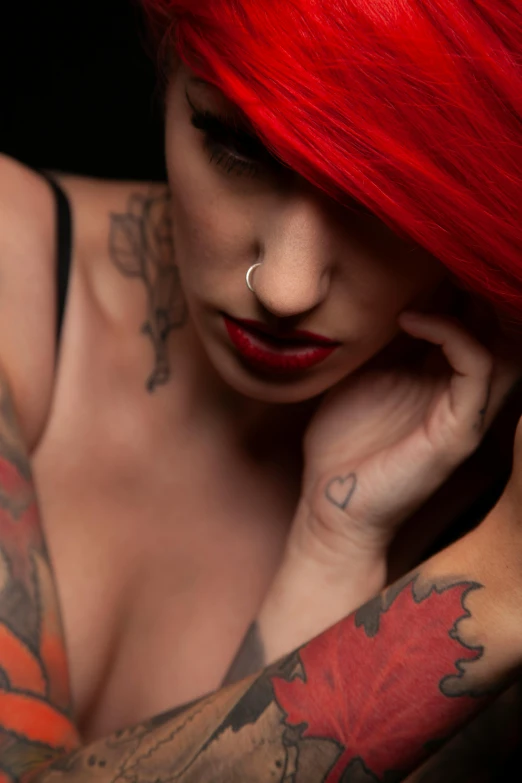 tattooed woman with red hair and piercing on her arm